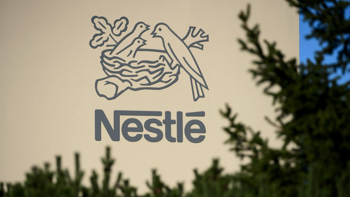 Nestlé logo displayed on a building exterior with tree branches in the foreground.