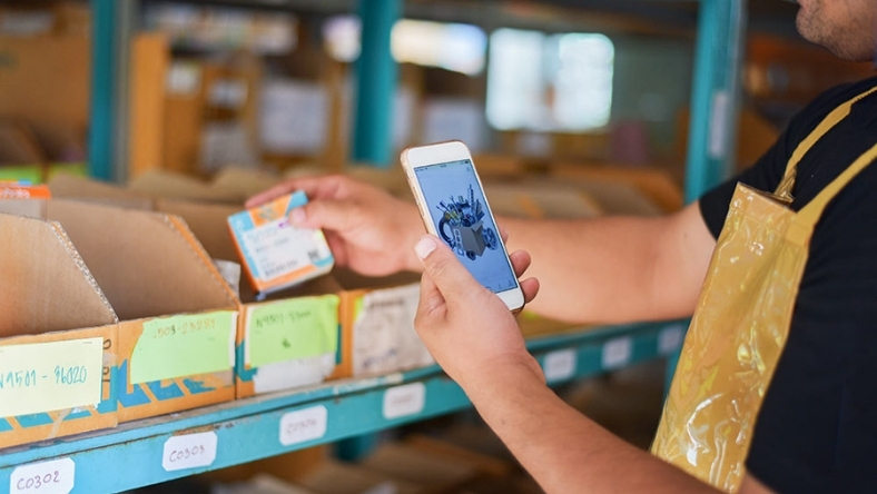 Worker scanning smart packaging label with a smartphone in a food warehouse
